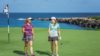 Two young female golfers walking on a green