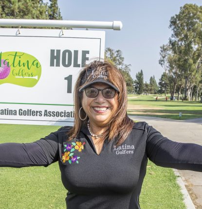 Azucena Maldonado of Latin Golfers Association in front of a golf hole sign for the Latina Golfers Association