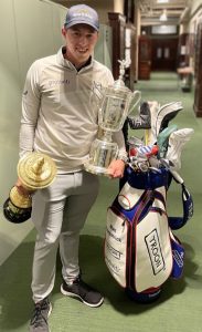 Matt Fitzpatrick standing next to his golf bag and holding U.S. Amateur and U.S. Open trophies