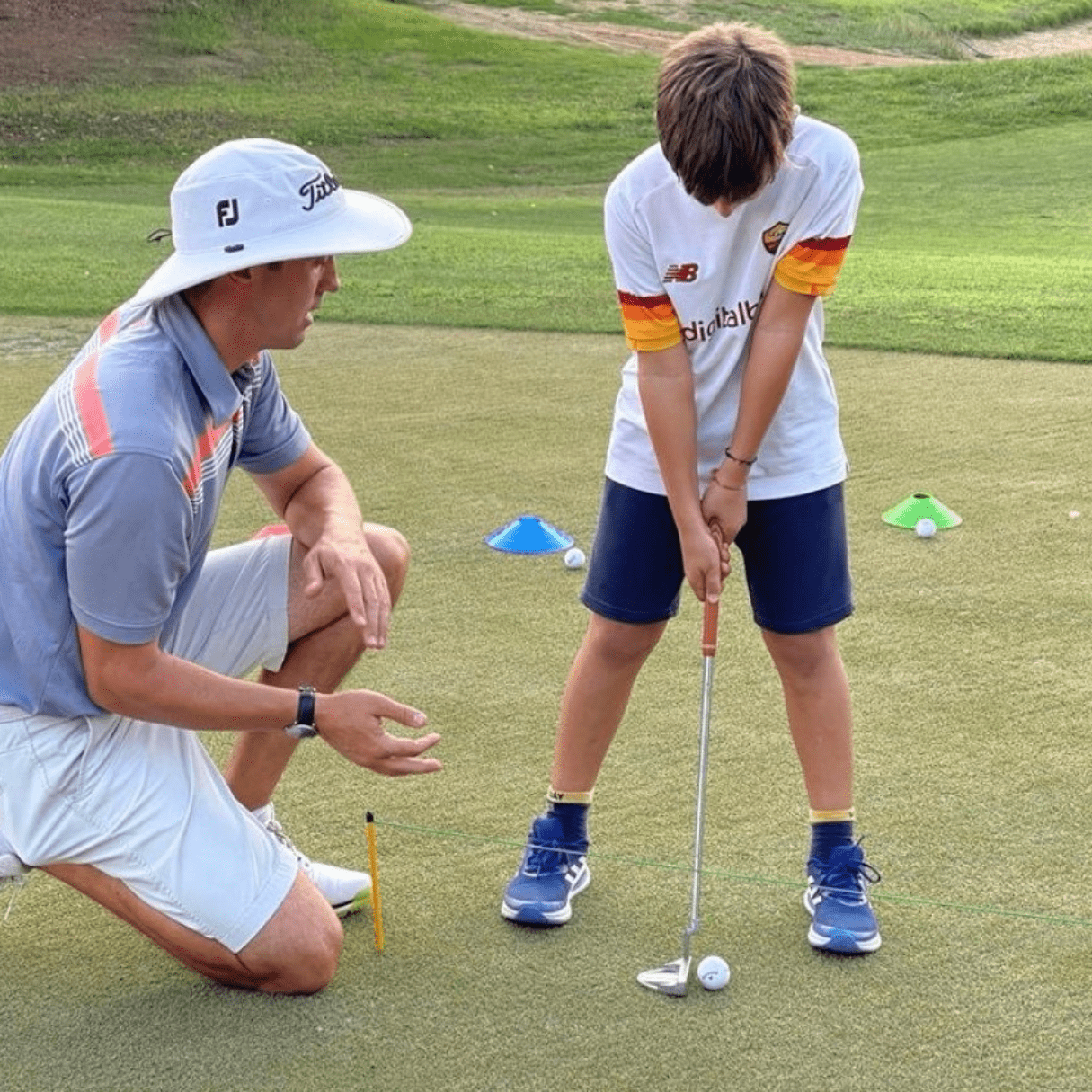 Damien Scott teaching professional at Al Hamra Golf Club teaching a junior golfer